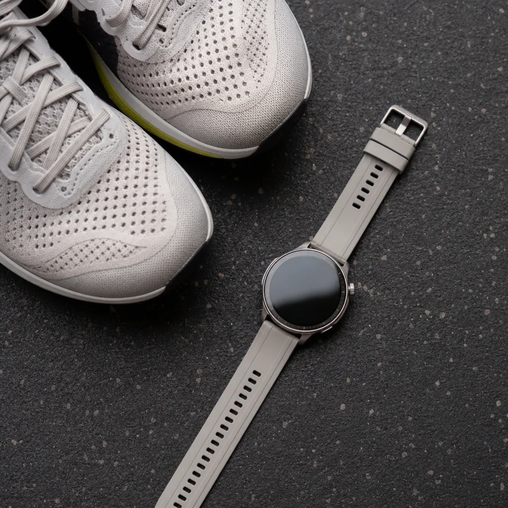 Titanium sports smartwatch showing workout data on a bright AMOLED display, placed on a gym floor
