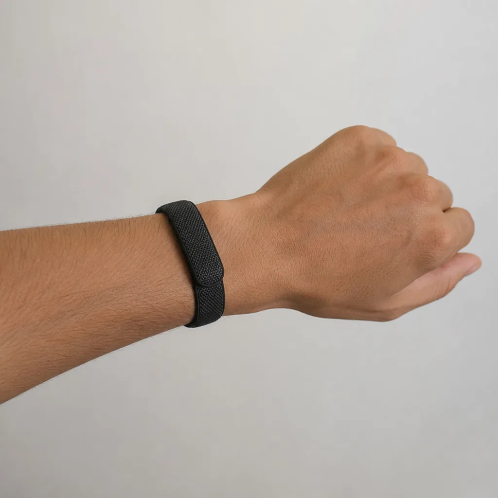 Screenless fitness tracker resting on a wooden desk next to a smartphone displaying health metrics
