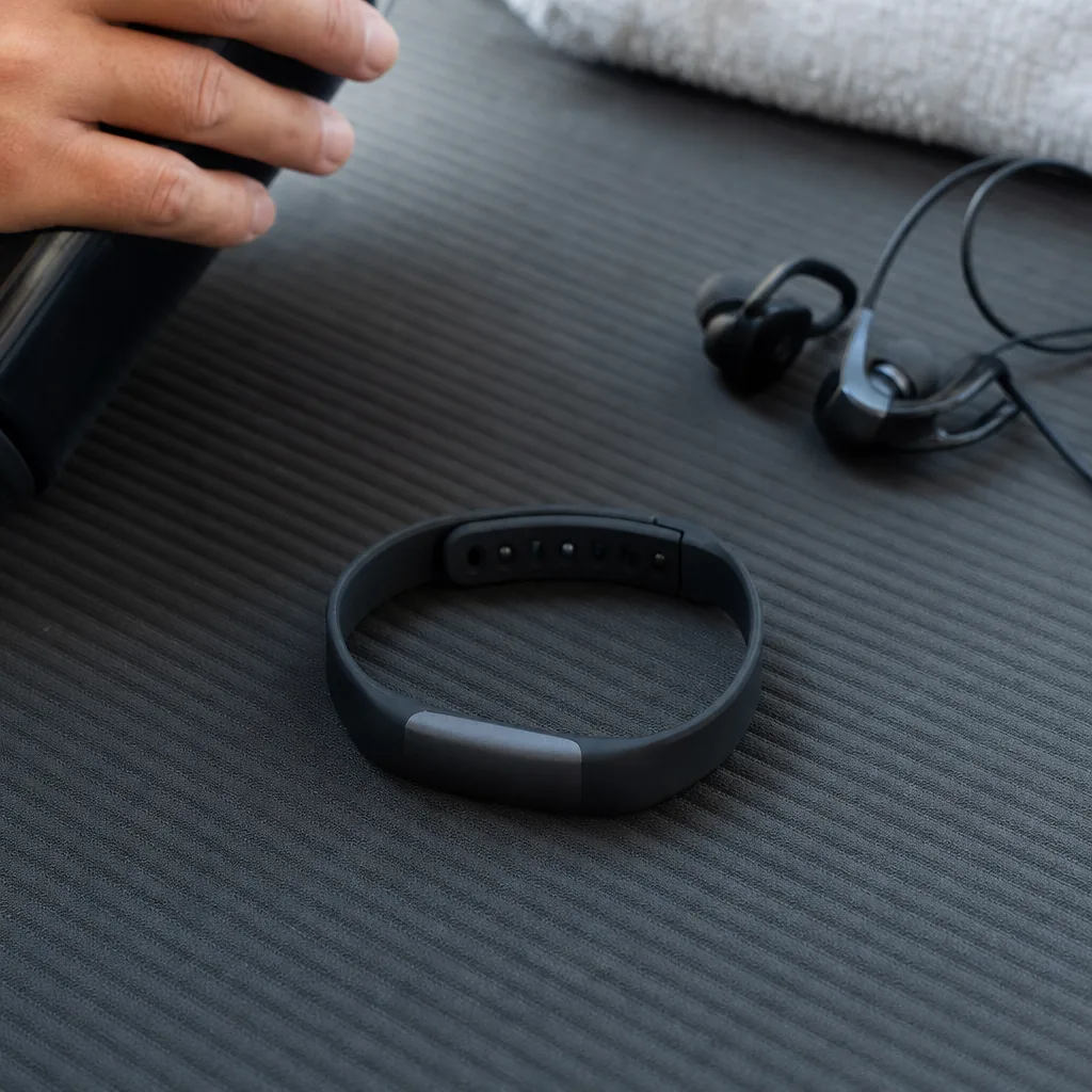 Screenless fitness tracker in a slim wristband next to a smartphone showing a health app dashboard