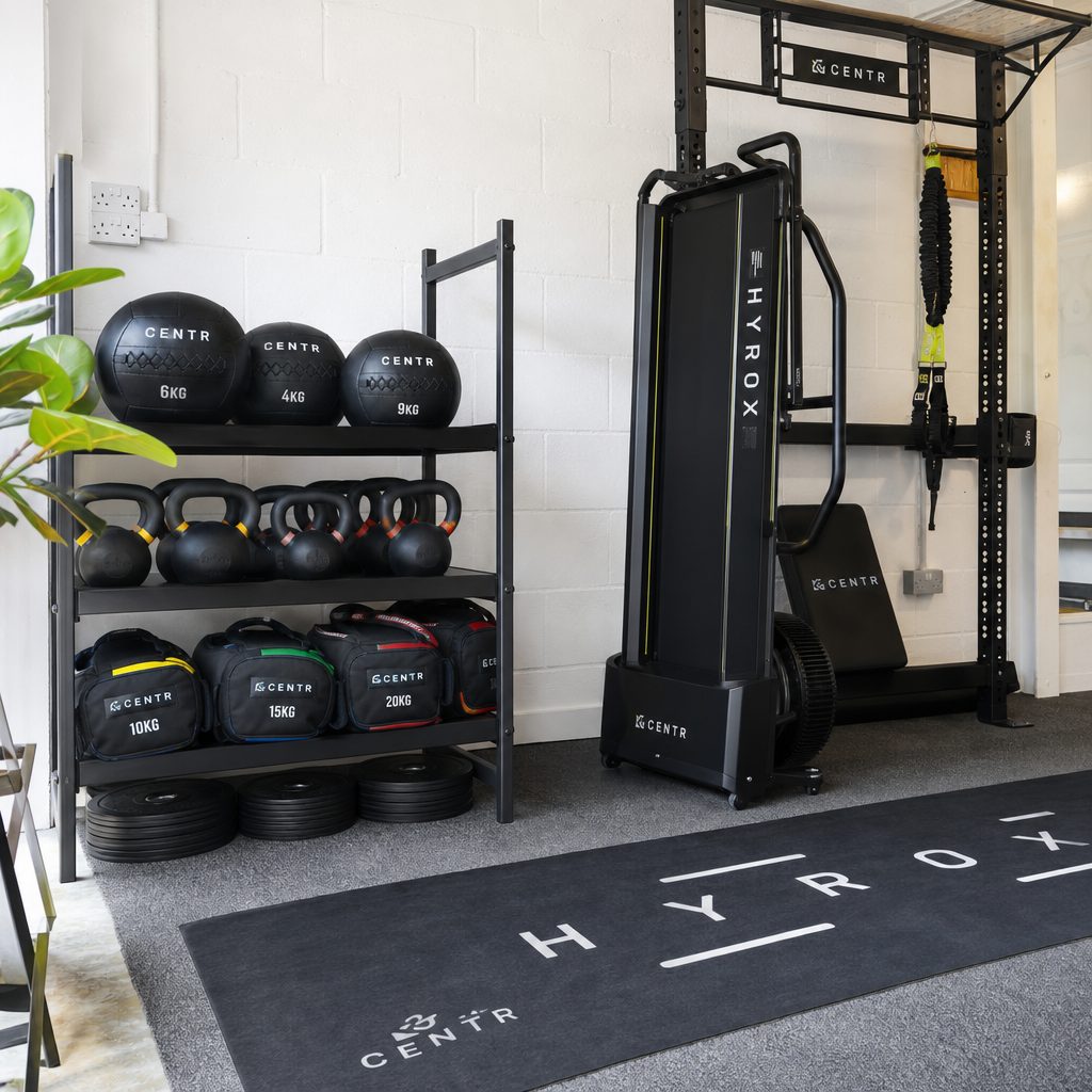 Wall balls, kettlebells and sandbags occupy little space when they are assigned a dedicated storage zone beside, rather than on, the training lane.